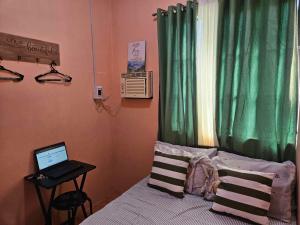 - une chambre avec un ordinateur portable sur un lit et une fenêtre dans l'établissement Mel's Place 2BR Apartment Unit1 in Batangas City, à Batangas City