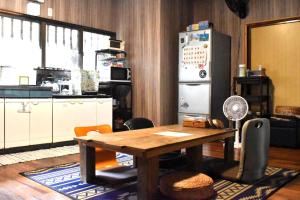 a kitchen with a wooden table and a refrigerator at 手広ビーチゲストハウス in Akaoki