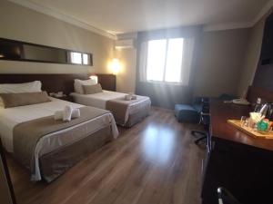 um quarto de hotel com duas camas e uma secretária em UH 714 Flat Aeroporto Congonhas em São Paulo