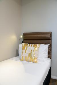 Una cama con una almohada blanca y dorada. en 57Hotel, en Sídney