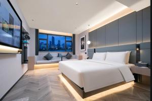een slaapkamer met een groot wit bed en een bank bij Atour S Hotel Ningbo Heyi Avenue in Ningbo
