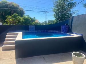 a swimming pool with a blue wall and stairs at Artista Helo Ceres0025 in Cuiabá