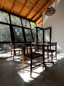 a table and chairs in a room with windows at Casa Raíz Cumbrecita in La Cumbrecita