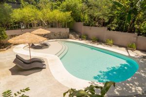 uma piscina com um guarda-sol e duas cadeiras e um guarda-sol em Altaroca Mountain Resort Antipolo em Antipolo