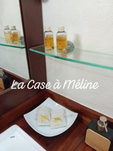 - une table avec 2 serviettes sur une assiette et 2 bouteilles de médicaments dans l'établissement La Case à Méline, au Gosier