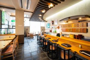 a restaurant with wooden tables and chairs and a chef preparing food at Hotel Patio Dogo in Matsuyama