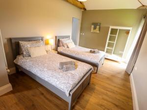 two beds in a room with wooden floors at Little Owl in Market Rasen