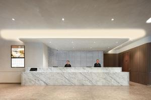 two men sitting at a reception desk in a lobby at Atour Hotel Ningbo Cixi Ancient Town in Ningbo