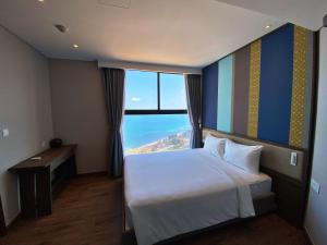 una camera d'albergo con un letto e una grande finestra di Apec Mandala Mũi Né - Khách Sạn Nghĩ Dưỡng Luxury Limited a Ấp Thiẹn Ái