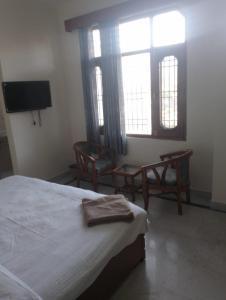 um quarto com uma cama e duas cadeiras e uma televisão em Hotel Marina Hills em Solan