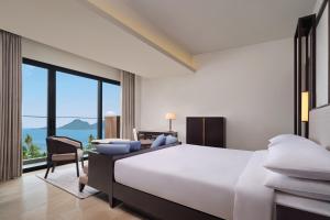 Schlafzimmer mit einem großen weißen Bett und einem Schreibtisch in der Unterkunft Lampung Marriott Resort & Spa in Lampung