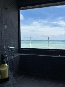 uma casa de banho com uma janela com vista para o oceano em CASA DUMAI OceanVilla NAKIJIN em Nakijin
