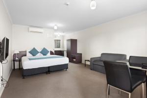 ein Schlafzimmer mit einem Bett, einem Sofa und einem TV in der Unterkunft Best Western BKs Pioneer Motor Lodge in Auckland