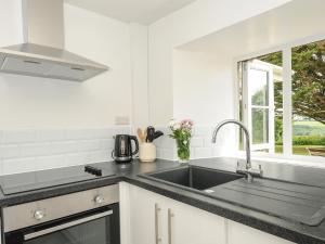 a white kitchen with a sink and a window at Lee Barton Farmhouse in Bude +25 photos