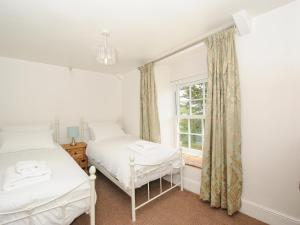 a bedroom with two beds and a window at Lee Barton Farmhouse in Bude