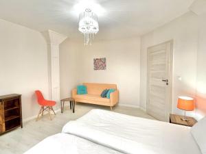 een witte slaapkamer met een bed en een stoel bij Apartament Karczyn - noclegi dla miłośników natury i spokoju in Karczy