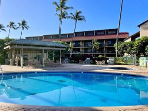 a swimming pool in front of a hotel with palm trees at Luana Kai Loft C308 BY Betterstay in Kihei