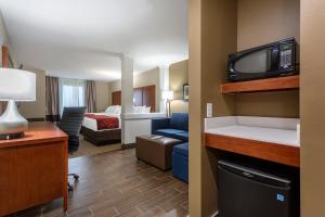 a hotel room with a room with a bed and a tv at Comfort Suites in Bowling Green