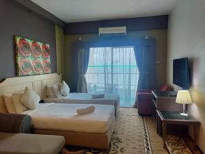 a hotel room with two beds and a window at Jazz Rainbow Paradise beachfront Peanag in Tanjung Bungah