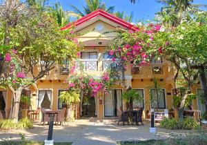 un bâtiment jaune avec des fleurs roses devant dans l'établissement Puerto Del Sol Beach Resort and Hotel Club Bolinao Pangasinan, à Bolinao