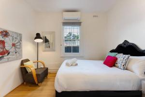 a bedroom with a large white bed and a chair at 4 bedroom Haven Spacious Terrace @Bondi Junction in Sydney