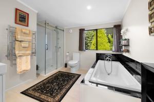 a bathroom with a large white tub and a toilet at Kings Summer House - Paihia Holiday Home in Paihia +18 photos