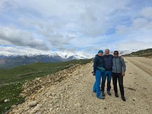 three people standing on the side of a dirt road at Zaur Guest hause in Xınalıq