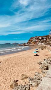 a beach with an umbrella and people on the sand at Casa Alicia @ Downtown in Mazatlán