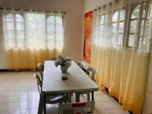 a dining room with a table with a vase of flowers on it at Olympia Travellers INN in Looc
