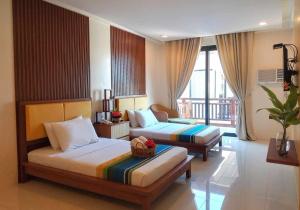 une chambre d'hôtel avec deux lits et un balcon dans l'établissement Puerto Del Sol Beach Resort and Hotel Club Bolinao Pangasinan, à Bolinao