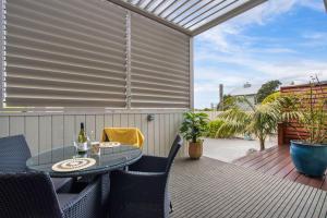 a patio with a table and chairs on a deck at Te Mahana Coastal Retreat in Waihi Beach