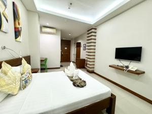 a bedroom with a large bed with a tv on the wall at Sunburn Suites and Rooftop Bar in Coron