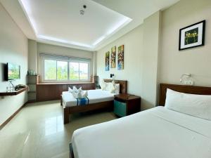 a hotel room with two beds and a window at Sunburn Suites and Rooftop Bar in Coron
