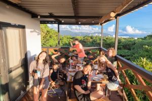 een groep mensen die aan een tafel op een balkon zitten bij Mambo Hostel Okinawa in Motobu