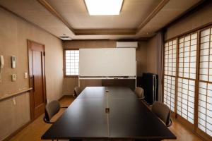 a conference room with a large table and a whiteboard at アウトドアコミュニティロッジ gosen～山梨の老舗アウトドアショップ ELKから生まれたロッジ～ in Minami Alps
