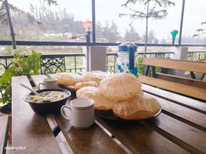 einen Tisch mit Gebäck und eine Schüssel Müsli und Kaffee in der Unterkunft SNR Cottage & Rooms in Udagamandalam
