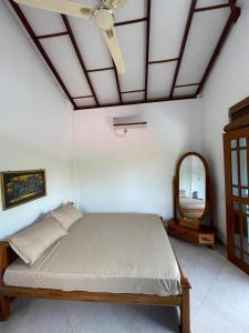 - une chambre avec un lit, un ventilateur de plafond et un miroir dans l'établissement Slater Villa, à Beruwala