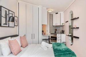 a bedroom with a white bed with pink and green sheets at 508 The Flamingo *Central* *Netflix* Aircon* in Cape Town