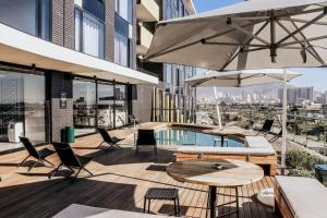 eine Terrasse mit Tischen und Stühlen und ein Pool auf einem Gebäude in der Unterkunft Modern Wex 831 in Kapstadt