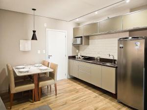 a kitchen with a table and a stainless steel refrigerator at Nosso Apê Cascatinha: Garagem | Ar-condicionado | Piscina | Sauna NA1304 in Juiz de Fora