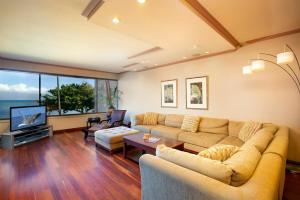 sala de estar con sofá y TV en Oceanfront corner unit w/ ac! sk215- Sullivan en Kahana