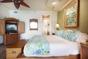 een slaapkamer met een bed en een flatscreen-tv bij Oceanfront corner unit w/ ac! sk215- Sullivan in Kahana