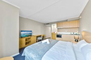 a bedroom with a large white bed and a kitchen at Comfortable King Bed Studio in Rose Hill with Parking in Sydney