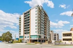 a tall white building on the corner of a street at Comfortable King Bed Studio in Rose Hill with Parking in Sydney