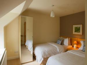 1 dormitorio con 2 camas y espejo en Attractive cottage in garden grounds en Jedburgh