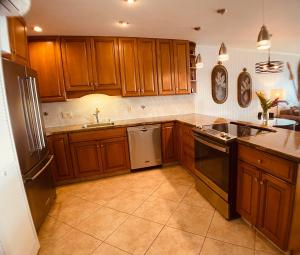 a kitchen with wooden cabinets and a sink and a dishwasher at Ocean views & dreamy sunsets! ks a7- Sullivan in Kahana +25 photos
