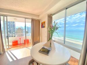 een woonkamer met een tafel met een vaas met bloemen bij Absolute beachfront main beach Gold Coast in Gold Coast