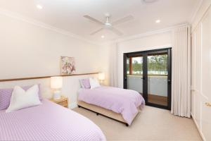 a white bedroom with two beds and a window at Neat Acres Farmhouse in Darawank