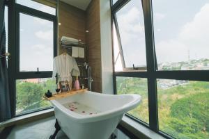 a bathroom with a white tub in front of windows at Greenview Hotel DaLat in Da Lat