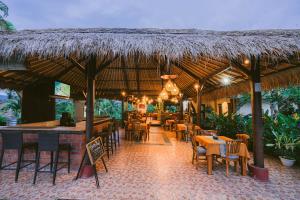 a restaurant with tables and chairs and a straw roof at Medewi Bay Retreat in Pulukan